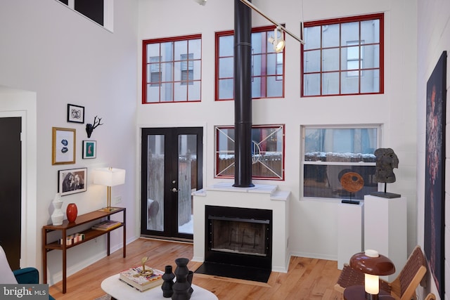 living room with french doors, a high ceiling, and light wood-type flooring