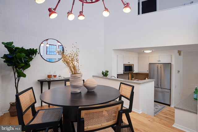 dining space with a towering ceiling and light hardwood / wood-style floors