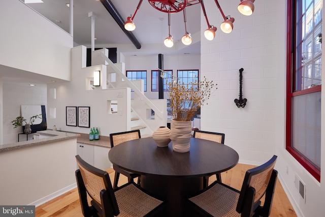 dining room featuring light hardwood / wood-style flooring and a towering ceiling