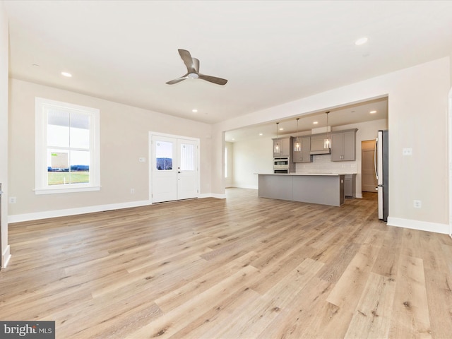 unfurnished living room featuring ceiling fan and light hardwood / wood-style floors