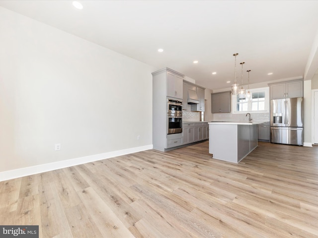 kitchen featuring a center island, gray cabinets, decorative light fixtures, light hardwood / wood-style floors, and stainless steel appliances