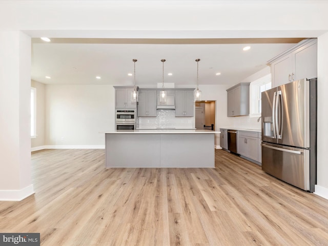 kitchen with pendant lighting, gray cabinetry, light wood-type flooring, appliances with stainless steel finishes, and a kitchen island