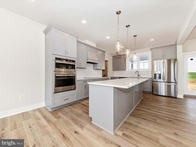 kitchen featuring appliances with stainless steel finishes, light hardwood / wood-style flooring, a kitchen island, and gray cabinetry