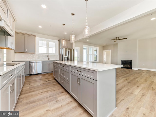 kitchen featuring gray cabinets, decorative light fixtures, a center island, and appliances with stainless steel finishes