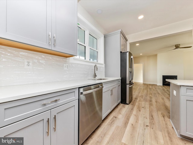 kitchen featuring decorative backsplash, stainless steel appliances, sink, light hardwood / wood-style flooring, and gray cabinets