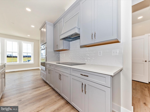 kitchen featuring gray cabinets, light wood-type flooring, and custom exhaust hood