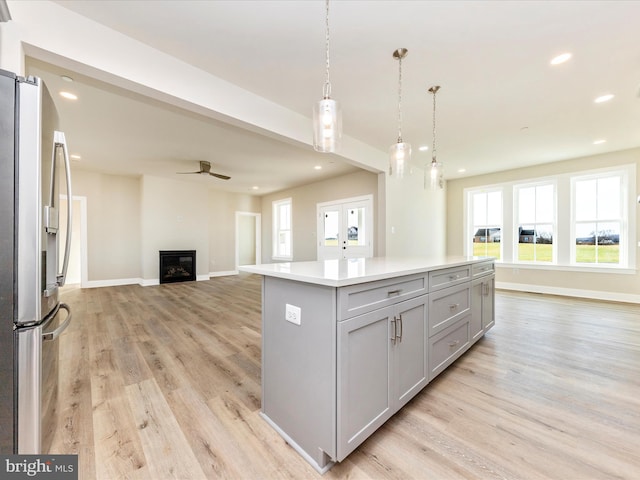 kitchen featuring gray cabinetry, stainless steel fridge with ice dispenser, a center island, and light hardwood / wood-style floors