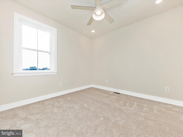 empty room featuring ceiling fan and light colored carpet