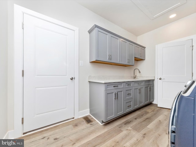 laundry room with cabinets, sink, and light hardwood / wood-style flooring