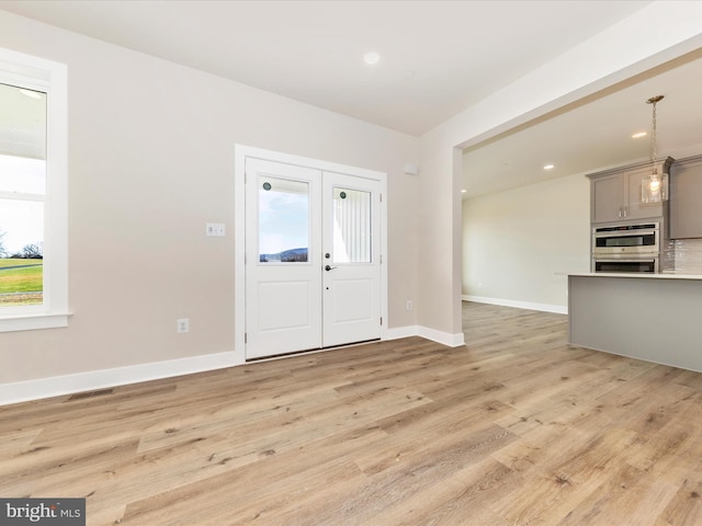 foyer entrance featuring plenty of natural light, french doors, and light hardwood / wood-style flooring