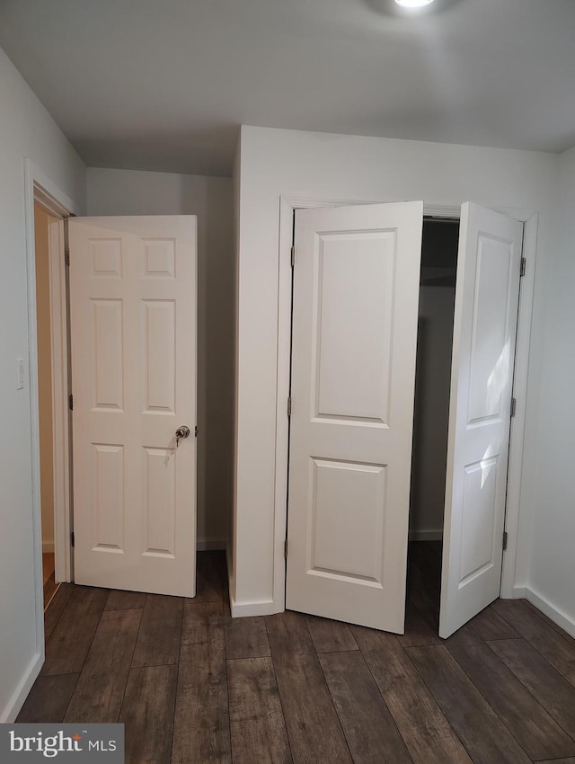 unfurnished bedroom featuring dark wood-type flooring and a closet