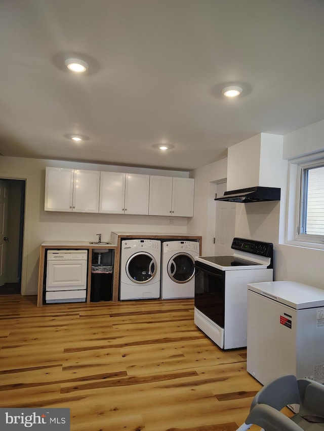 washroom with washing machine and dryer and light wood-type flooring