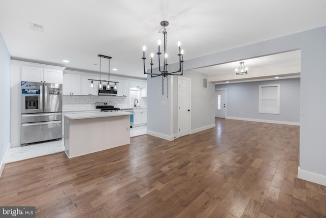 kitchen with white cabinets, stainless steel appliances, dark hardwood / wood-style floors, and decorative light fixtures