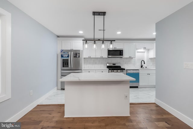 kitchen featuring stainless steel appliances, a center island, hardwood / wood-style floors, hanging light fixtures, and white cabinetry