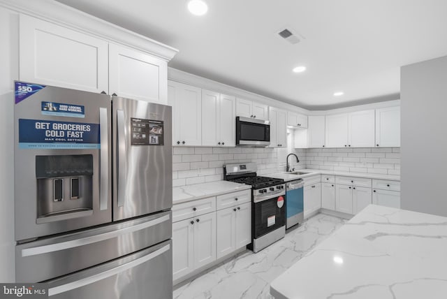 kitchen with stainless steel appliances, light stone counters, white cabinets, decorative backsplash, and sink