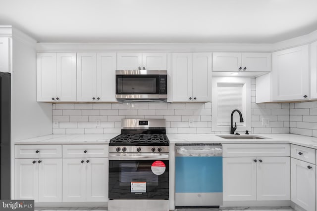 kitchen featuring stainless steel appliances, white cabinets, sink, and light stone counters