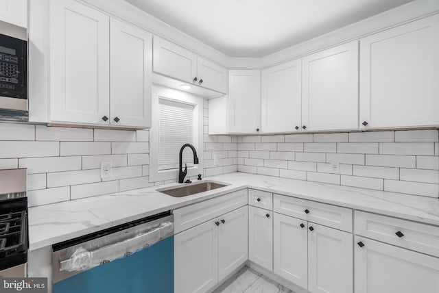 kitchen with stainless steel appliances, white cabinetry, backsplash, light stone countertops, and sink