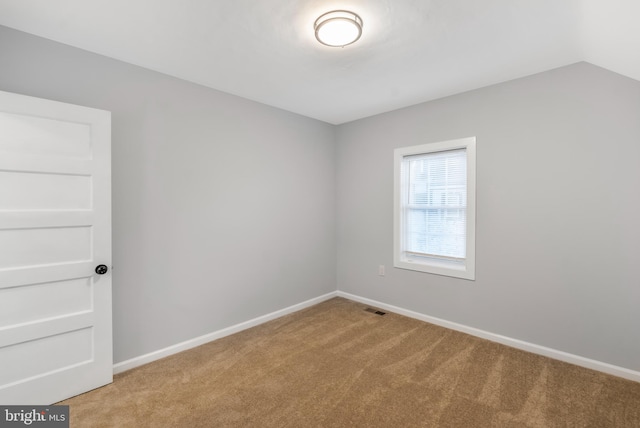 spare room with vaulted ceiling and light carpet