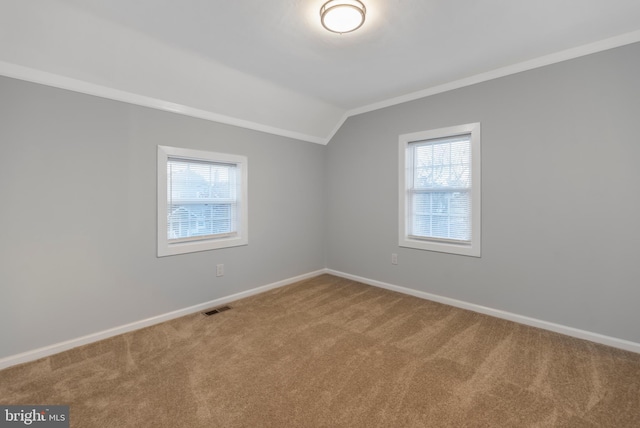 carpeted empty room with vaulted ceiling, crown molding, and plenty of natural light