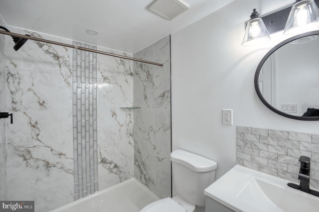 bathroom with toilet, vanity, and tiled shower