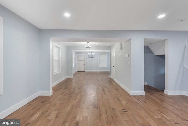 unfurnished living room featuring light hardwood / wood-style floors and a notable chandelier