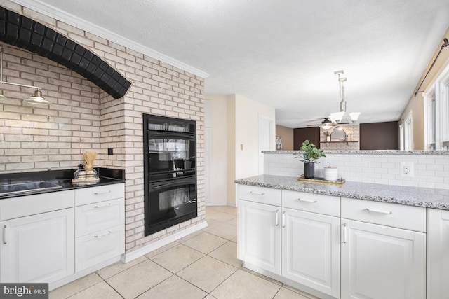 kitchen with tasteful backsplash, light tile patterned flooring, a glass covered fireplace, white cabinets, and dobule oven black