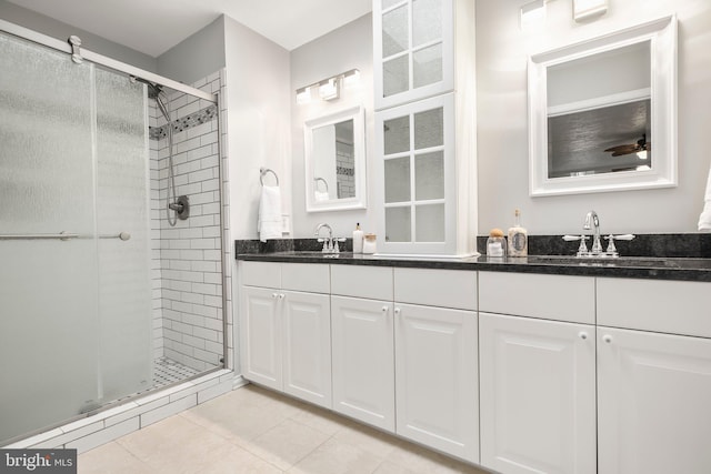 full bathroom with a sink, double vanity, a shower stall, and tile patterned flooring