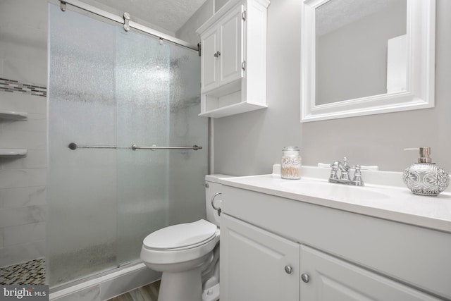 full bathroom featuring vanity, a shower stall, toilet, and a textured ceiling