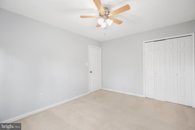 unfurnished bedroom with a closet, baseboards, light colored carpet, and ceiling fan