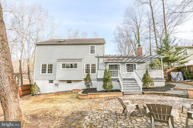 back of property featuring a deck, fence, a pergola, and a chimney