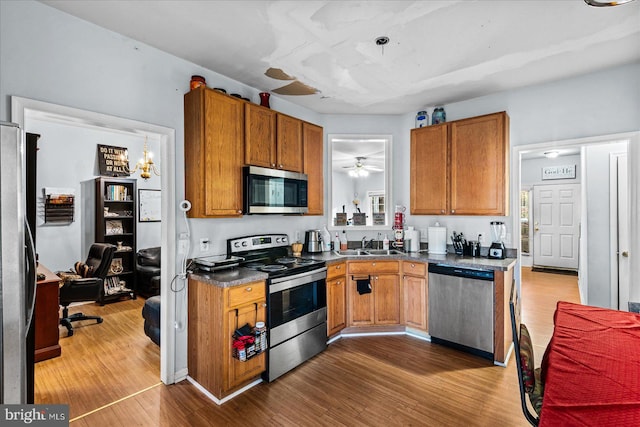 kitchen featuring ceiling fan with notable chandelier, hardwood / wood-style flooring, and stainless steel appliances