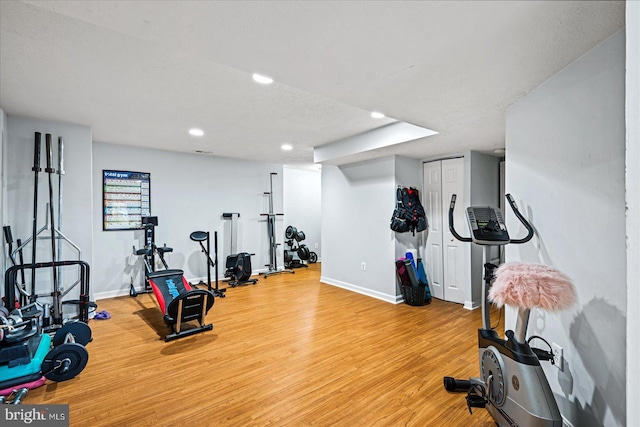 exercise area with a textured ceiling and light wood-type flooring