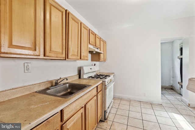 kitchen featuring white gas range, sink, and light tile patterned flooring