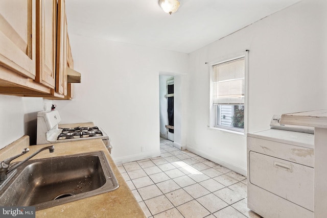 kitchen featuring white range with gas cooktop, sink, light tile patterned floors, and washer / dryer