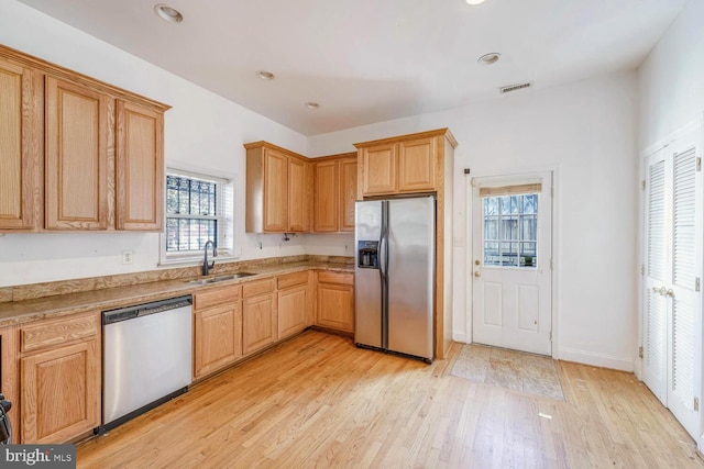 kitchen with light wood-type flooring, stainless steel appliances, a wealth of natural light, and sink