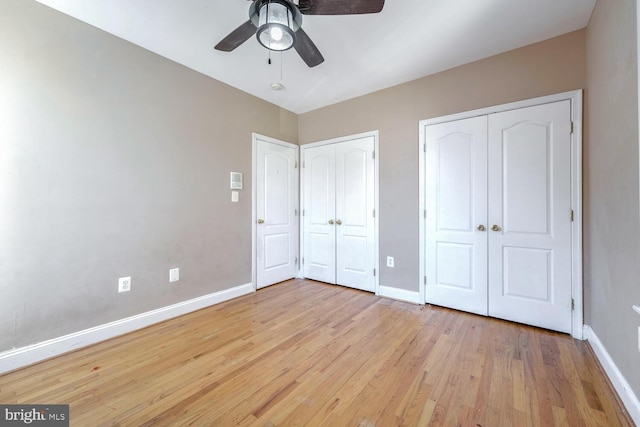 unfurnished bedroom featuring ceiling fan, light hardwood / wood-style floors, and two closets