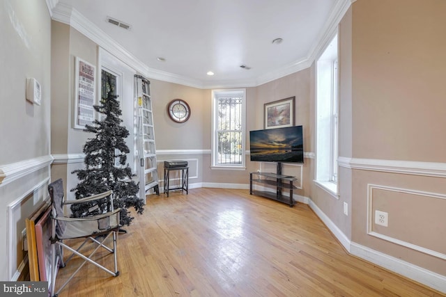 living area with light wood-type flooring and ornamental molding