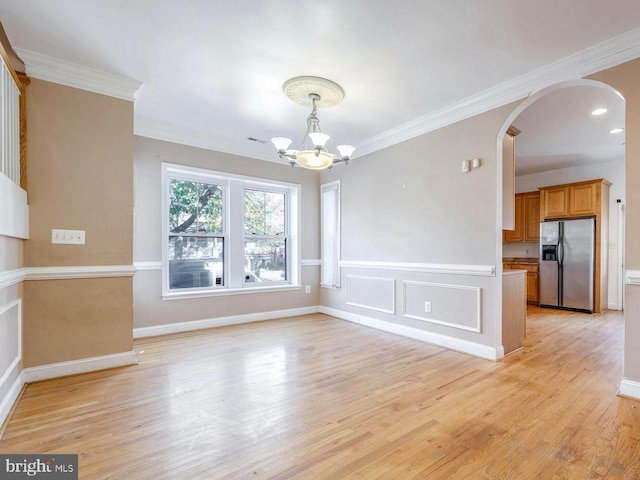 unfurnished dining area with light hardwood / wood-style floors, ornamental molding, and a notable chandelier