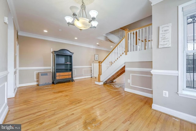 unfurnished living room featuring crown molding, hardwood / wood-style floors, and a chandelier