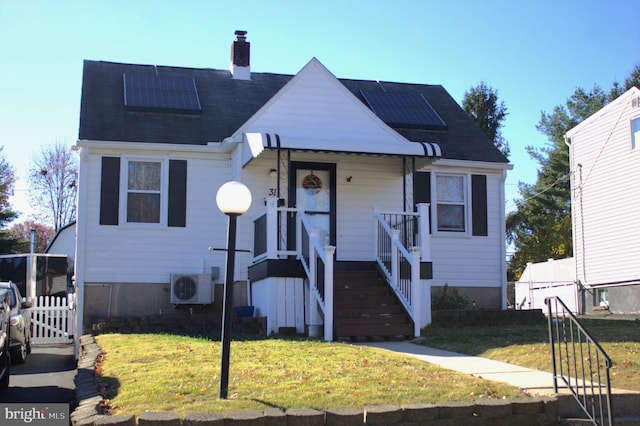 view of front of property featuring solar panels, ac unit, and a front yard