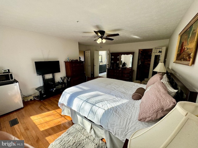 bedroom featuring hardwood / wood-style floors, a textured ceiling, fridge, and ceiling fan