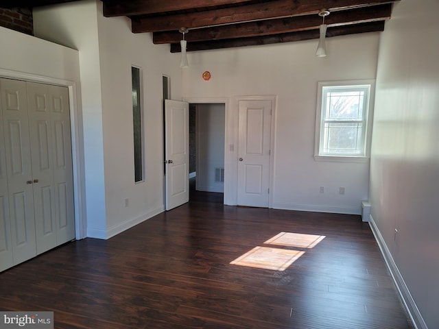 unfurnished room featuring dark wood-style floors, baseboards, and beam ceiling