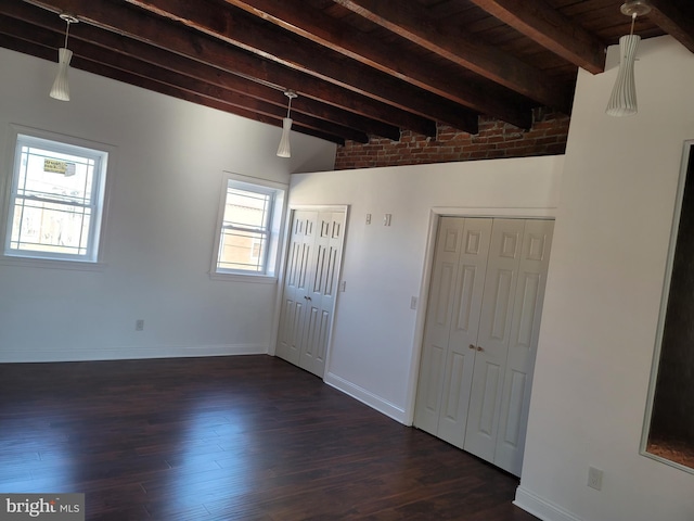 empty room with beamed ceiling, healthy amount of natural light, dark wood-style floors, baseboards, and wooden ceiling