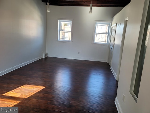 spare room with dark wood-type flooring, baseboards, and beam ceiling