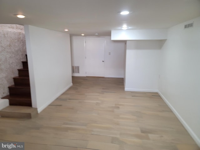 finished basement featuring baseboards, light wood-style flooring, stairs, and recessed lighting