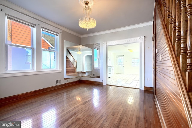 entryway with ornamental molding, wood-type flooring, and a notable chandelier