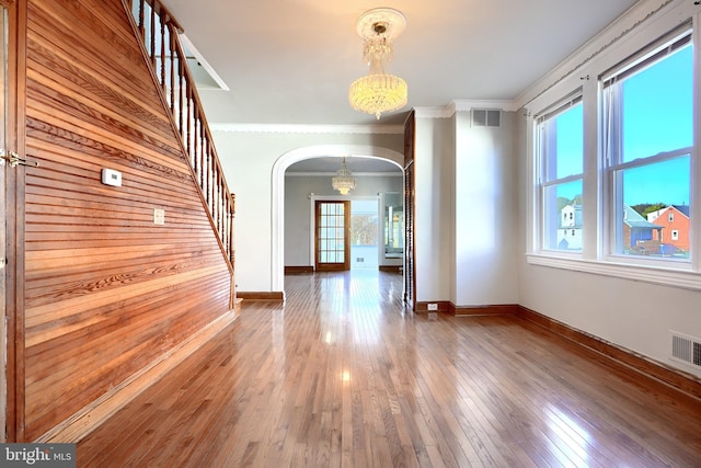 unfurnished room with crown molding, plenty of natural light, wood-type flooring, and wood walls