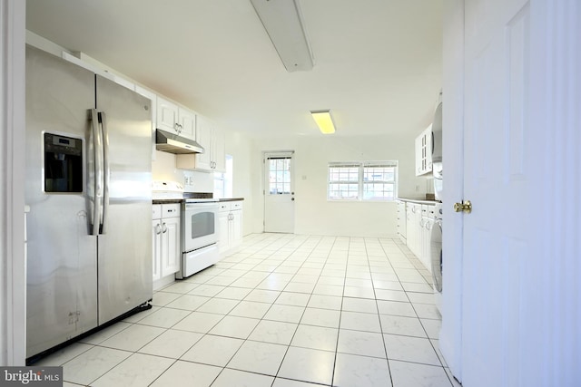 kitchen featuring white electric range oven, stainless steel fridge, light tile patterned floors, and white cabinetry