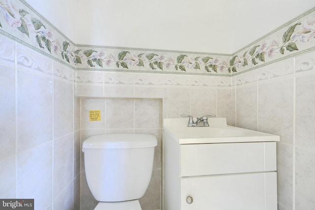 bathroom with vanity, toilet, and tile walls