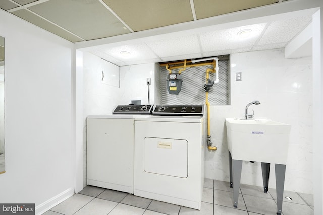 laundry room with washer and clothes dryer, light tile patterned flooring, and sink